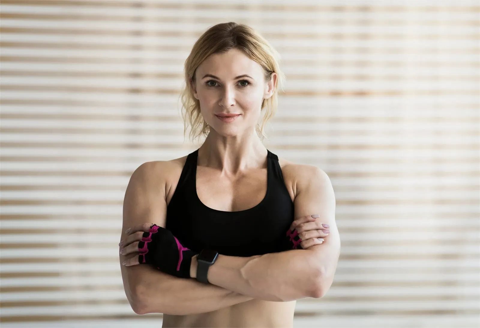 Fit woman with arms crossed in a bright studio